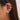Close-up of a woman wearing gold diamond-studded hoop earrings with visible facial features including forehead, hair, nose, lips, chin, and eyebrow.