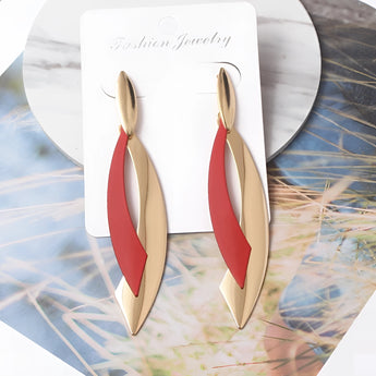 Gold Feather & Green Leaf Dangle Earrings with chic modern design displayed against a wooden background.