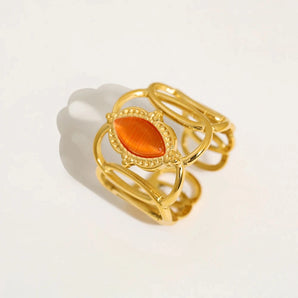 Gold filigree bracelet with an orange gemstone, made from luxurious materials, showcasing intricate design and craftsmanship.