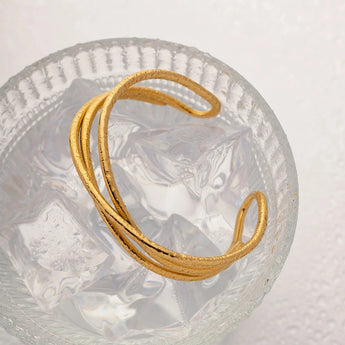 Gold heart bracelet with adjustable minimalist open heart bangle design on a white background.