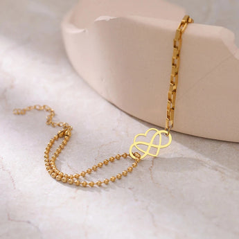 Elegant adjustable gold heart charm bracelet displayed on a beige surface, featuring dainty and fashionable design, perfect as a jewelry gift.