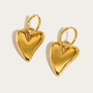 Gold heart dangle earrings in a gold tone, designed by YA-CHAN, displayed on a human body.