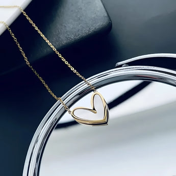 Gold heart pendant necklace with a minimalist design, displayed on a clean background, showcasing its romantic charm and elegant simplicity.
