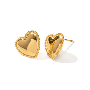 Gold heart stud earrings with a minimalist design, made of gold metal, displayed on a human hand.
