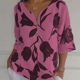 A woman wearing a pink dress accessorized with a gold layered coin pendant necklace, featuring detailing charms on a thin chain. The outfit complements the necklace, creating a chic and elegant look.