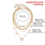 Gold layered necklaces set with pearl pendant, featuring a chunky chain and stylish chokers, worn around a woman's neck.