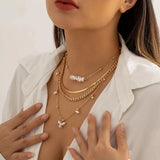 Woman wearing a set of gold layered necklaces with a pearl pendant, featuring chunky chains and stylish chokers.