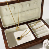 Gold locket necklace featuring black onyx and white stone in a two-tone design, displayed on beige background.