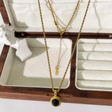 Gold locket necklace featuring a black onyx and white stone, two-tone jewelry gift.