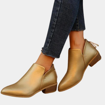 Gold metallic ankle boots with pointed toes and a low heel, featuring a zipper design. The boots showcase a sleek and fashionable style, made from a leather material, displayed on a human leg.