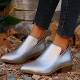 Gold metallic pointed toe zipper ankle boots with a fashion low heel, styled with denim fabric in an outdoor setting; footwear modeled on a human leg.