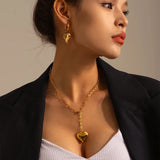Gold and silver heart charm pendant worn on a woman's neck, showcasing a romantic and versatile jewelry gift.