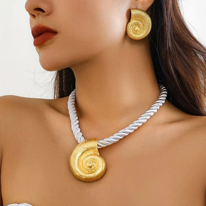 A woman wearing gold spiral earrings and a rope twist necklace, showcasing high-end fashion jewelry.