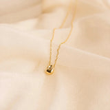 Gold stainless steel minimalist pendant necklace, hypoallergenic and tarnish-resistant, showcased on a beige fabric background.