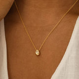 A minimalist gold stainless steel pendant necklace worn on a woman's neck, showcasing its hypoallergenic and tarnish-resistant properties.