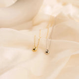 Gold stainless steel minimalist pendant necklace, hypoallergenic and tarnish-resistant, displayed on a natural material background.