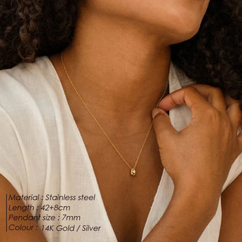 Gold stainless steel pendant necklace displayed on model's neck, hypoallergenic and tarnish-resistant, minimalist design.