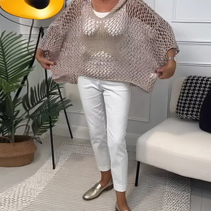 Gold-tone metallic knit poncho with sequin embellishments, draped over a shoulder, showcasing a flowy textile ideal for a summer cover-up.