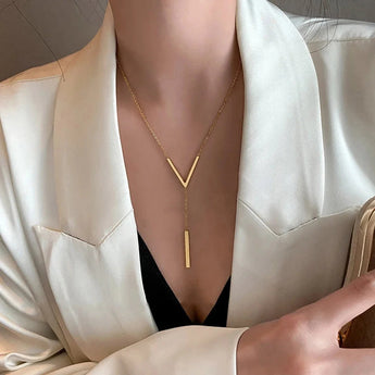 Gold V-shaped minimalist vertical bar pendant necklace displayed on a model's neck and chest, with the necklace resting elegantly against the collarbone.