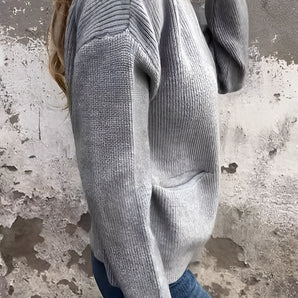 Gray oversized ribbed knit sweater on a woman, showcasing its cozy, casual design perfect for winter wear. The sweater features long sleeves and a soft, comfortable fit, with the fabric draping over the waist and hips. The color is a versatile grey, suitable for pairing with various outfits.