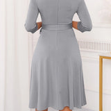 Gray plus size midi dress featuring a tie-waist and button-front design, ideal for casual work settings. The dress is modeled by a person, showcasing its one-piece garment style with focus on the shoulder and neck areas.