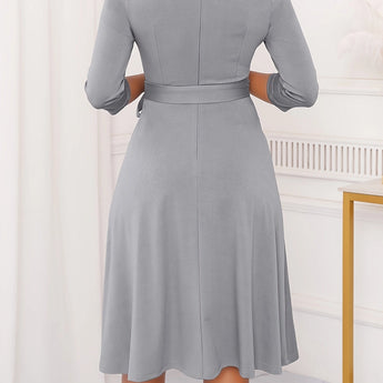 Gray plus size midi dress featuring a tie-waist and button-front design, ideal for casual work settings. The dress is modeled by a person, showcasing its one-piece garment style with focus on the shoulder and neck areas.