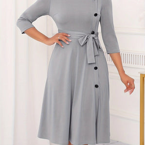 Gray plus size midi dress featuring a tie-waist and button-front design, suitable for casual work settings; includes long sleeves and a tailored fit for a flattering silhouette.