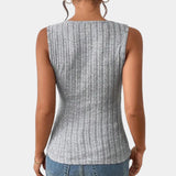 A woman wearing a gray ribbed sleeveless tank top with a deep V-neck and button details, paired with jeans.