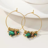 Gold hoop earrings with green crystal pendants from YA-CHAN Luxury Designer Jewelry displayed on a white background.