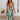 Green floral wrap midi dress with a V-neck and sleeveless design, worn by a smiling person with styled hair, showcasing the dress's elegant fit and comfortable spring fashion appeal.