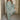
Woman wearing a green geometric long sleeve midi dress with a fitted waist, collar, and knee-length hem, perfect for fall fashion. She is smiling, adding a cheerful vibe to the outfit.