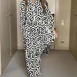 
A woman wearing a green geometric long sleeve midi dress, showcasing fall fashion. The dress features a fitted waist and a stylish design, highlighting the sleeves and neckline.
