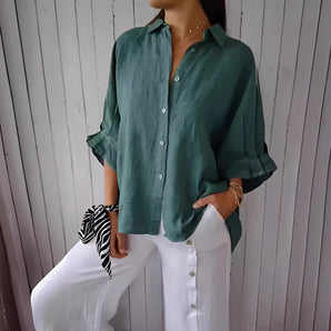 Women's relaxed fit button-down blouse in dark green linen, featuring long sleeves, a structured collar, and button details, displayed on a mannequin.