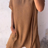 A woman wearing a green linen tunic dress with oversized and breathable design, featuring casual summer style, short sleeves, and a loose fit.