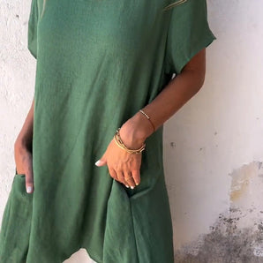 A woman wearing a green linen tunic dress, featuring an oversized and casual summer design with breathable fabric and stylish details.