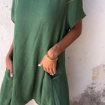 A woman wearing a green linen tunic dress, featuring an oversized and casual summer design with breathable fabric and stylish details.