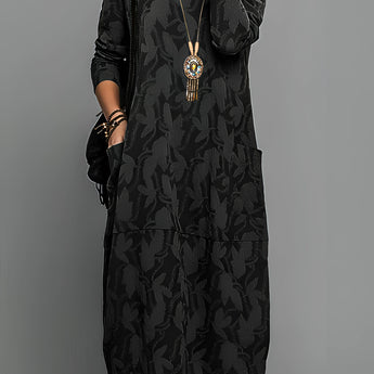 Green patterned long sleeve midi dress worn by a person standing, paired with a tribal necklace. The dress features a one-piece design with a fitted shoulder and arm, suitable for day wear.