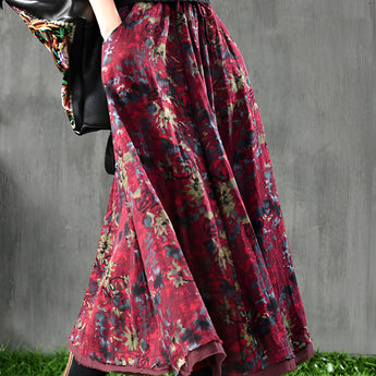 
Woman wearing a green ribbed sweater paired with a floral maxi skirt, showcasing a fall fashion outfit. The sweater features long sleeves and a fitted waist, while the skirt has a mix of pink and red floral patterns.
