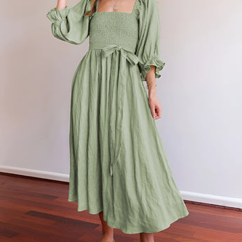 Green smocked dress with a ruched square neckline, featuring long sleeves and a fitted waist, designed as a women's day dress for spring.