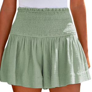 Woman wearing a green smocked summer skirt with elastic waist and ruffles, standing outdoors.