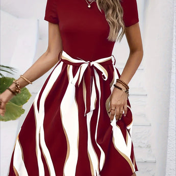 A woman wearing a casual summer green striped belted flare dress with short sleeves.