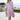 Woman wearing a pink striped button-down summer dress with a cinched waist and short sleeves, standing with hands on hips.