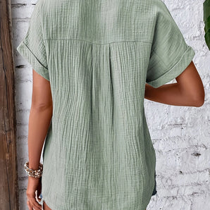 A woman wearing a green textured pleated back blouse, lightweight and short-sleeved, made of cotton.