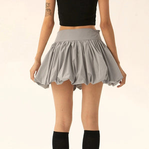 Grey high-waisted pleated tennis skirt worn by a woman, showcasing its athletic mini skirt design.