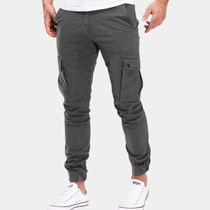 Men's grey slim fit cargo pants with multiple pockets, styled for street fashion, worn with white sneakers.