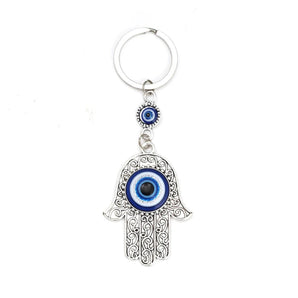 Hamsa Hand Evil Eye Keychain with blue spiritual charm, featuring intricate metal design and electric blue accents, used as a protective amulet.