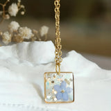 Handmade gold flower resin pendant featuring real botanical elements, designed as a unique gift and fashion accessory.