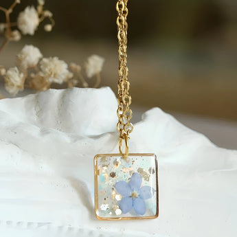 Handmade gold flower resin pendant featuring real botanical elements, designed as a unique gift and fashion accessory.