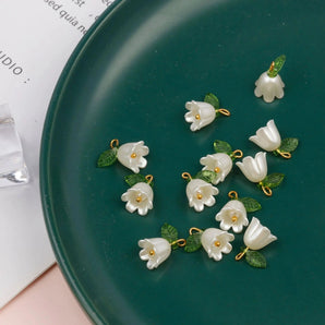 Handmade porcelain flower earrings with white blossom and leaf detail displayed against a plain background.