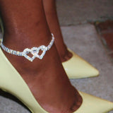 Heart-shaped diamond bridal anklet adorning a woman's ankle, elegant wedding foot jewelry with a sparkling charm.